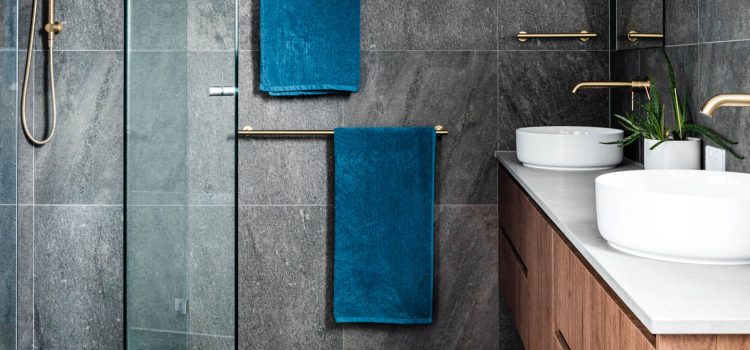 Brass taps with dark grey tiles